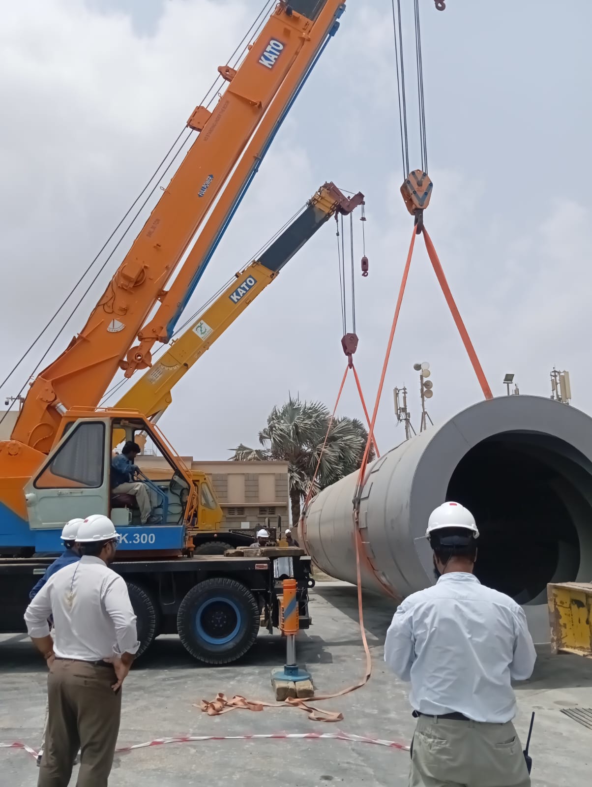 Mobile crane lifting a fabricated cylindrical tank at an industrial site